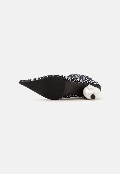 Chaussure à bout pointu à motif noir et blanc vue de la semelle, avec un talon rond blanc sculpté unique.