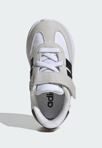 Biele a šedé atletické topánky vyrobené z semišového a sieťového materiálu, so suchým zipsom, čiernymi pruhmi a štruktúrovaným vnútorným podšívkou.