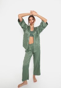 Groene gestreepte pyjama set van soepel materiaal; losse top met brede mouwen, bijpassende broek met elastische tailleband, minimalistisch ontwerp.