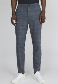 Šedé kárované kalhoty s přizpůsobeným střihem, vybavené hladkým předním dílem a zapínáním na knoflíky, doplněné bílými teniskami.