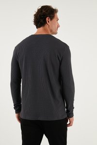 Langärmliges, geripptes T-Shirt in Dunkelgrau mit Rundhalsausschnitt und strukturiertem Stoff, ausgestattet mit enganliegenden Ärmeln und einem lässigen Schnitt.