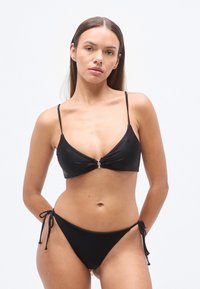 Bikini noir avec un haut triangulaire moulé, une fermeture avant, des bretelles fines et ajustables, et un bas taille basse avec des fermetures latérales à nouer.