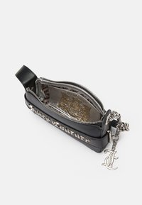 Fekete bőr táska ezüst hardware-rel, cipzáras záródással és lánccal. Belsejében arany mintázatú bélés található, az oldalán pedig a márka felirata.