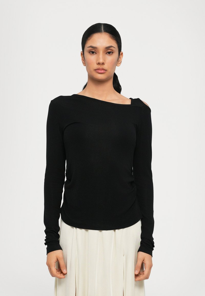 Maglietta nera a maniche lunghe realizzata in tessuto morbido, con scollo asimmetrico e dettaglio spalle scoperte, completata da una silhouette aderente.