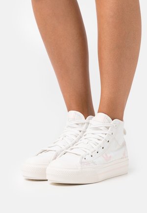 Sneakers alte bianche con tomaia in tela liscia, suola di gomma strutturata e sottili accenti rosa con un logo sul lato.