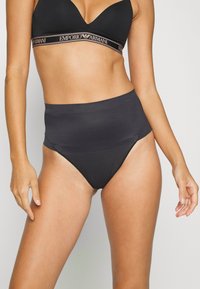 Culotte noire taille haute avec une texture lisse, dotée d'une large ceinture. Fabriquée en tissu extensible pour un confort et un ajustement optimal.