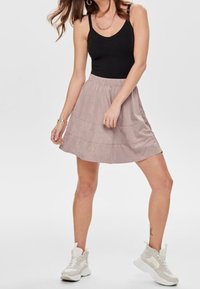 Černý tílko, světle růžová sukénka s volány a bílé tenisky. Sukénka má měkkou texturu a elastický pás pro pohodlí.