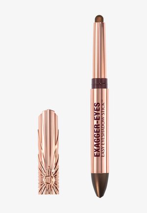 Crayon ombre à paupières rétractable en or rose avec une teinte marron foncé, étiqueté Exagger-Eyes, et un capuchon décoratif assorti placé à côté.