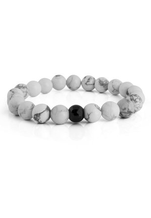 Des perles rondes en marbre blanc avec des veines grises et une perle noire brillante forment un bracelet extensible sur une surface blanche réfléchissante.