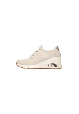 Sneaker beige in maglia con chiusura frontale con lacci, suola imbottita con camera d'aria visibile e suola esterna in gomma marrone chiaro.