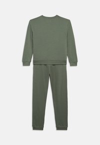 Σκούρο πράσινο φούτερ και αντίστοιχες φόρμες. Μαλακό ύφασμα με ριμπ μανσέτες και ζώνη. Απλός σχεδιασμός, χωρίς σχέδια ή ορατά εξαρτήματα.