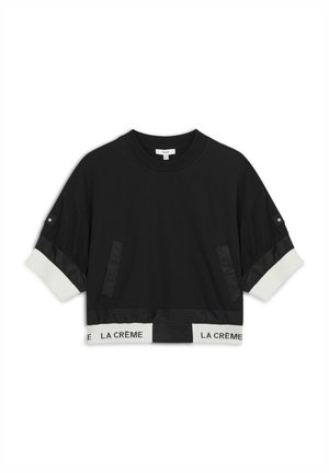 Felicità nera accorciata con fascia elastica bianca che presenta il testo "LA CRÈME". Include dettagli in pannello di satin e due tasche laterali.