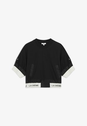 Sweatshirt noir court avec bande élastique blanche comportant le texte "LA CRÈME". Comprend des détails en satin et deux poches latérales.