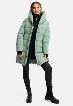 Light mint green padded coat with a high collar, zip closure, and side pockets, worn over a black top and jeans, paired with black ankle boots.