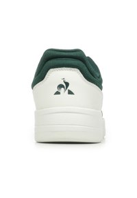 Groene en witte sneaker met een geweven bovenkant, gevoerde kraag en een logo op de hiel. Rubberzool met een gladde afwerking.