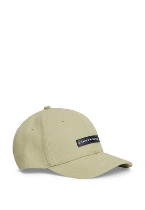 Gorra de béisbol beige claro con visera curva y un pequeño parche rectangular negro que dice "Tommy Hilfiger" en la parte frontal.