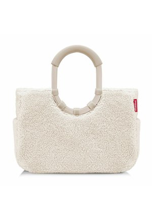 Sac en fausse fourrure crémeux avec une poignée arrondie beige. Forme rectangulaire, texture douce, présentant une petite étiquette logo rouge sur le côté.
