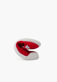 Zapatos de tela rojos con suelas de goma blanca, con un interior suave, tiras elásticas y un diseño flexible para un fácil uso.