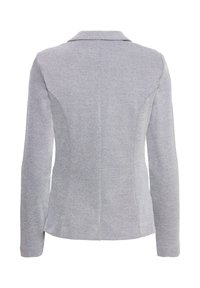 Veste blazer grise avec un tissage texturé, col cranté, coupe ajustée, manches longues et détails de couture au dos.