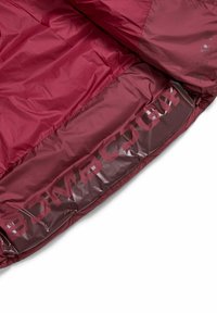 Giacca a vento bordeaux con tessuto lucido. Presenta un testo di marca audace sulla fodera e una shell esterna testurizzata. Design leggero e portatile.