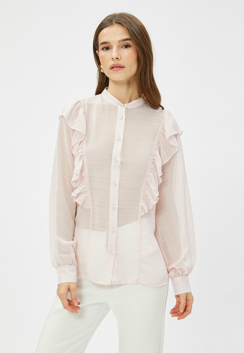 Lys pink skjorte med volangdetaljer, knapåfront, lange ærmer og en subtil stribet tekstur. Glat stof med en let gennemsigtig udseende.