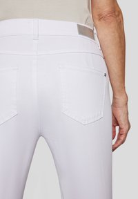 Helle Lavendel-Jeans mit glatter Textur, ausgestattet mit zwei Gesäßtaschen und einem metallischen Etikett am Bund. Lässiges Design, geeignet für verschiedene Styles.