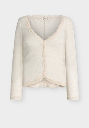 Beige ribbed long-sleeve cardigan with scalloped lace trim along neckline, button placket, and hem, featuring small buttons down center front.