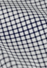 Katoenen stof met een wit en marineblauw geruit patroon, met kleine vierkanten in afwisselende kleuren en texturen, wat diepte creëert.