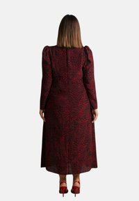 Červené a černé dlouhé šaty s leopardím vzorem, užší korzet a áčková sukni. Nosené s červenými lodičkami na tenkých podpatcích.