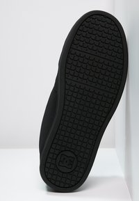 Sort skate sko sål med et tekstureret gummimønster og riller for greb, kontrasterende logo ved hælen og et rent design.