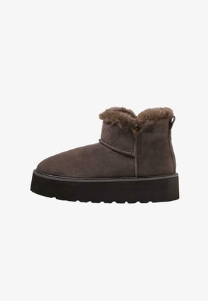 Bottines en suede marron avec un col en fausse fourrure, un bout rond et une semelle noire épaisse. Équipées d'une languette à l'arrière pour un enfilage facile.