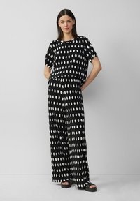 Ensemble à motifs noir et blanc composé d'un haut ample à manches courtes et d'un pantalon à jambes larges avec un design de pois irrégulier.