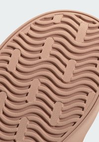 Gumová podrážka v měkké růžové barvě. Obsahuje vlnitý vzor dezénu s texturovanými povrchy a vyvýšenými částmi pro trakci a uchopení.