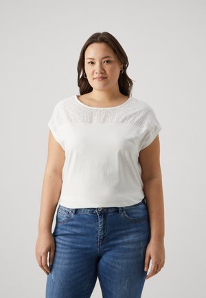 Hvit T-skjorte med korte ermer, med detaljer i øyelet ved yoken. Mykt stoff med en avslappet passform, kombinert med blå denimjeans.