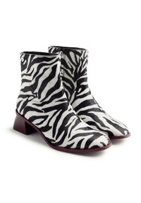 Botas de tobillo con estampado de cebra en blanco y negro, con una textura suave, punta afilada y un tacón bajo cuadrado.