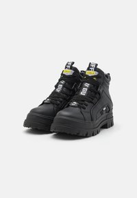 Black high-top sneakers with textured leather, thick rubber sole, and prominent laces. Features branding on tags and side. Chunky design.