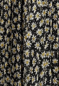 Tela negra con un patrón floral que presenta margaritas blancas con centros amarillos, dispuestas en un diseño plisado con pequeños puntos blancos.