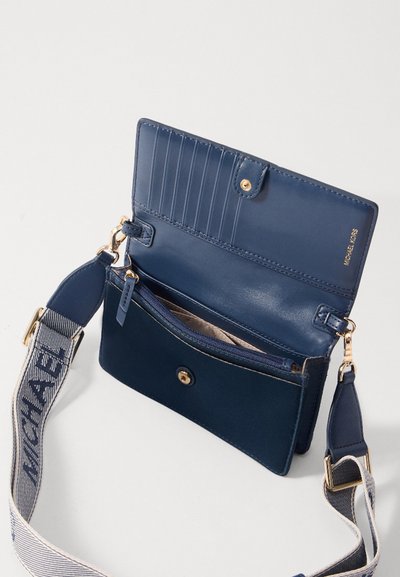 Sac bandoulière en cuir bleu marine avec un fermoir à pression doré, plusieurs emplacements pour cartes, poche zippée et une sangle à motif.