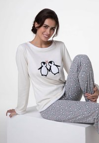 Maglietta crema a maniche lunghe con grafica di pinguino e cuore rosa; pantaloni grigi con motivo di pinguini e cuori; tessuto di cotone liscio.