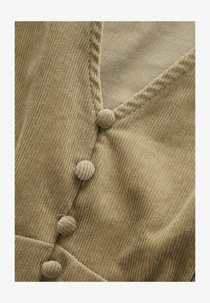 Indumento in corduroy beige caratterizzato da un profondo scollo a V con quattro bottoni rivestiti in tessuto, che mette in risalto una superficie morbida e testurizzata.