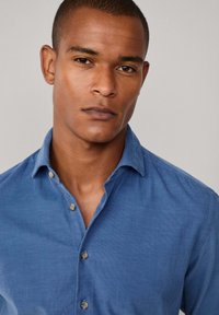 Blauw, knoopshirt van lichtgewicht stof met een subtiele textuur. Voorzien van een gespreide kraag en contrasterende knopen.