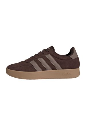 Baskets basses marron Adidas avec une semelle beige et trois bandes beiges sur le côté, vue latérale avec lacets et languette de talon de marque.
