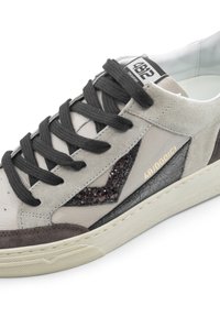 Sneaker aus hellgrauem Wildleder und Leder, schwarzen Schnürsenkeln sowie einer strukturierten schwarzen und glitzernden Akzentuierung. Verfügt über eine cremefarbene Gummisohle und ein goldenes Logo.