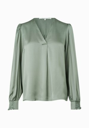 Heledest roheline pluus, mis on valmistatud kergest kangast, V-kaelusega, pikkade varrukatega ja kogutud mansettidega. Esiküljel on peened voldid.