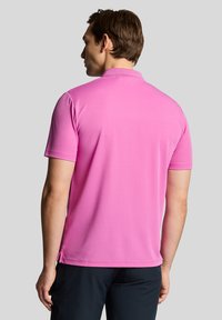 Men's short-sleeve polo shirt in bright pink, made of smooth fabric with a classic collar, featuring side slits for comfort and mobility.