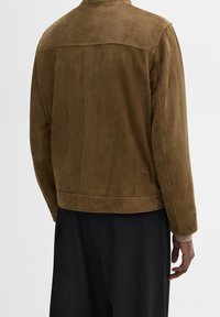 Giacca in suede marrone con una texture liscia, design senza colletto e cuciture minimaliste. Presenta una vestibilità dritta e maniche scese.