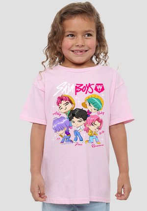 Smiling child with curly hair wearing a pink t-shirt featuring colorful cartoon characters and "Saja Boys" text.