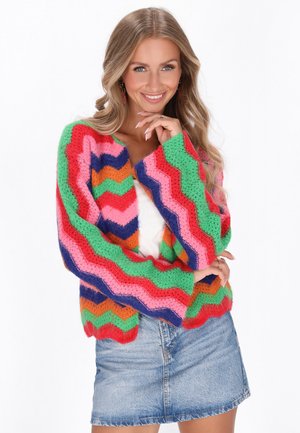 Kleurige gebreide cardigan met zigzagpatroon in roze, groen, oranje en blauw. Losse pasvorm en lange mouwen. Draag over een witte top.