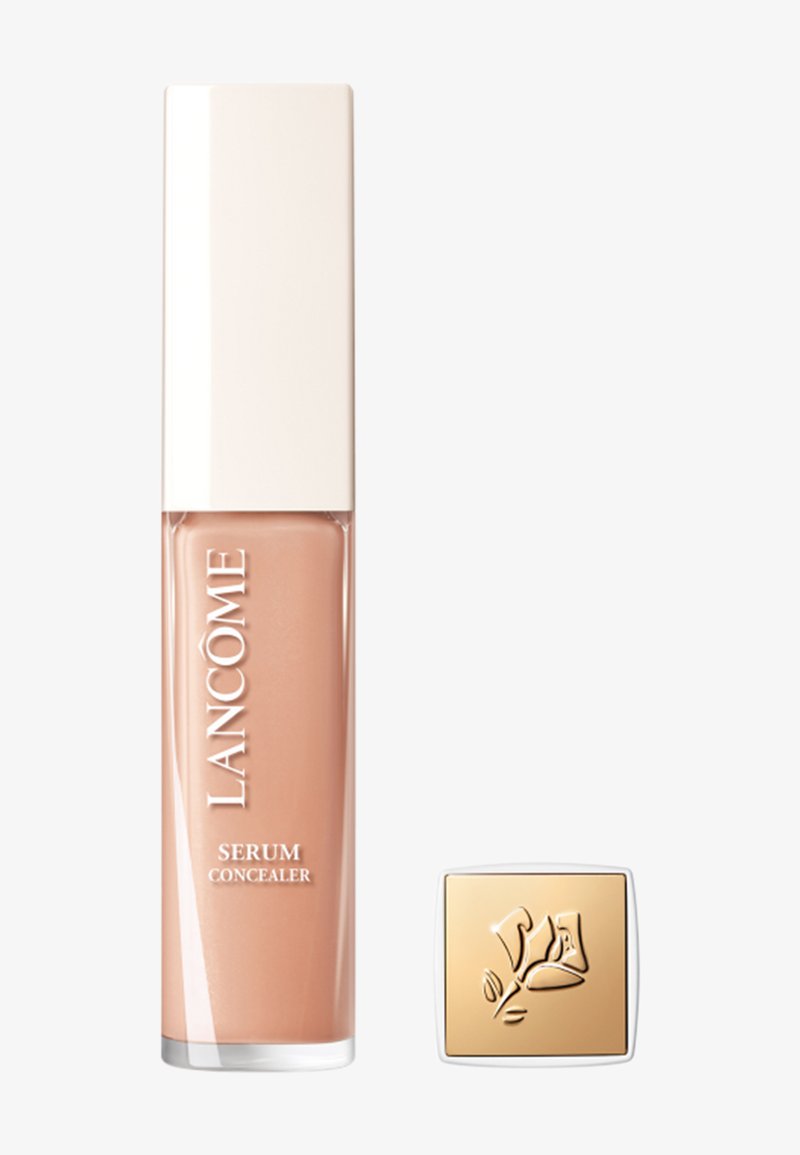 Correcteur Sérum Lancôme dans un tube rectangulaire clair, avec une formule crémeuse beige clair. Le capuchon carré orné d'accents dorés présente un motif floral.