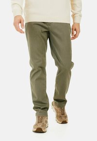 Olijfgroene broek van katoenmix, met een rechte pijp, stikseldetails en gedragen met lichtbruine sneakers.